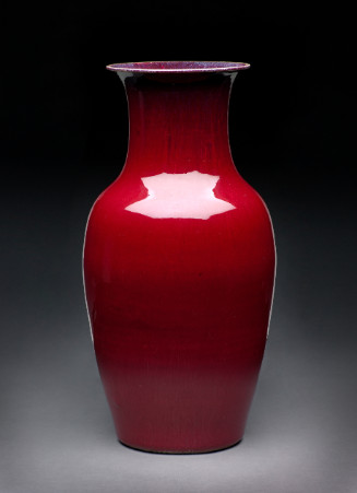 A sleek, baluster-shaped ceramic vase with a highly reflective, solid deep red glaze. It features a sharply flared rim, a gently sloping neck, and wide shoulders that taper smoothly to a flat base. 