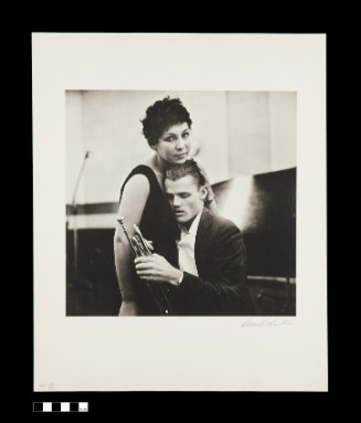 Standing female and seated male figures, female leans against male with her head resting on his. He holds a trumpet.