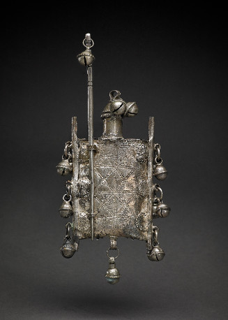 Rectangular vessel with rounded stopper, "saddle bag" design with bangle bells attached.  Inscribed surface of overlapping diamonds.  Stick mounted through loop on side, has bangle bell on handle end.