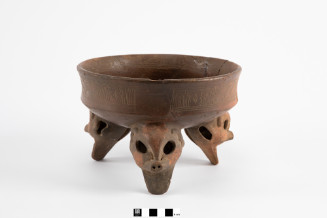 Large bowl with rounded bottom, angle break at wall, with slight inward slope and slight outward flare of rim, supported by tripod legs shaped as large animal heads - hollow globes with cut holes for eyes, raised nose ridge with small pig’s snout, small mouth opening underneath with extended "jaw" slab for foot, rattles inside; inscribed panels of vertical lines, diagonals with "toothed" zig-zags, diamonds, bordered by multiple incised lines