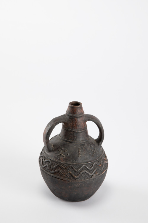 Bottle with two opposed handles extending from narrow neck to belly; central register with raised X marks and undulating lines and inscribed columns of chevrons; adorned with white seed beads
