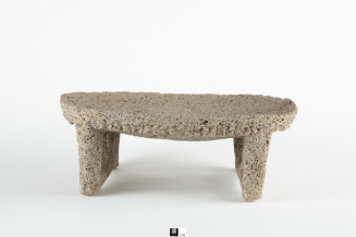 Four legged metate with oval shaped, rimmed, grinding plate, small nubbins on borders.