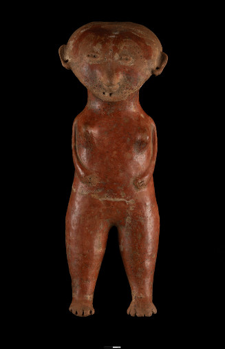 Standing female figure, frontal, small arms attached to body with hands placed on sides of abdomen, thick legs, tapering to foot with indicated toes.  Head in flattened and heart shaped protruding nose with rings, coffee bean eyes, two poke marks for mouth ears pierced, figuring in red slip, white pigment indicates groin flap, traces of white along hairline and around eyes, white indicating ankle bracelets.