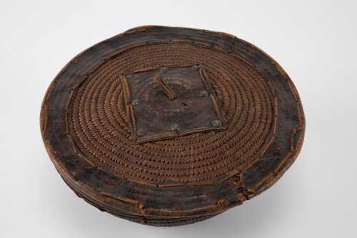 Basket with hemispherical body, flat lid, and stitched leather.