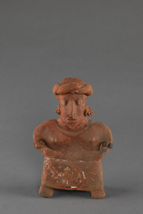 Standing female with ankle length skirt; arms curve inward with hands on stomach; very flat, wide torso and chest; large head and nose; twisted head tie; ornamentation at ears, neck and elbows; slightly raised breasts with small knobs; geometric design